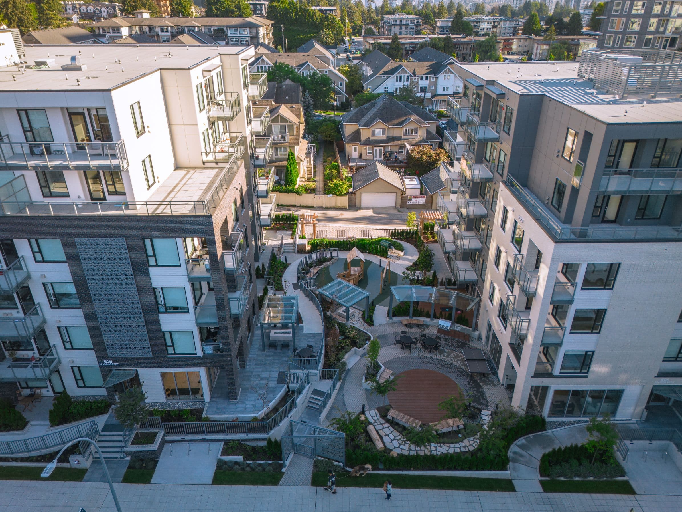 The Seasons courtyard from above, between the two buildings — paths, pergolas, seating and the play area